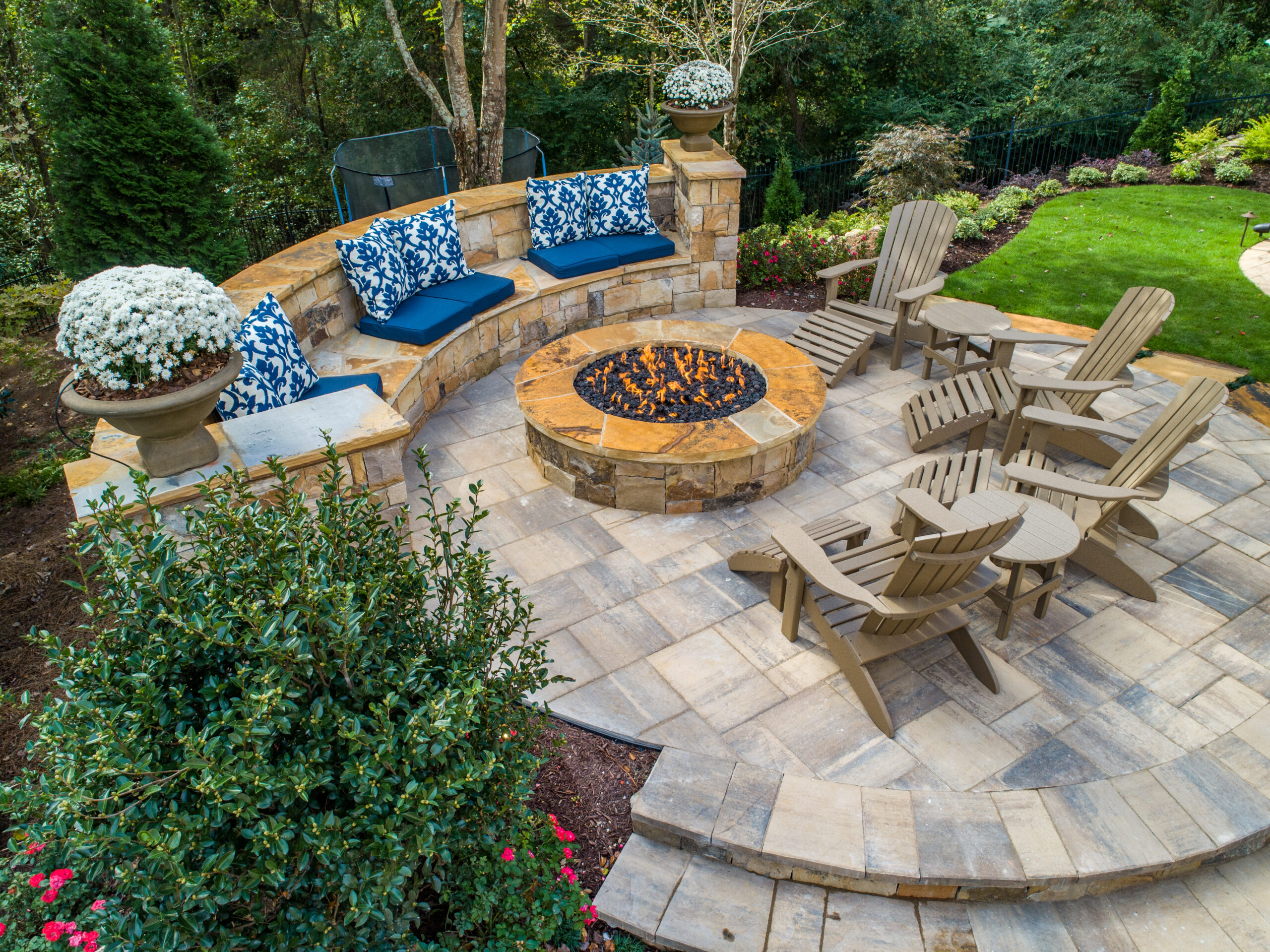 An overhead shot of a stone patio with a flagstone fire pit surrounded by lush greenery