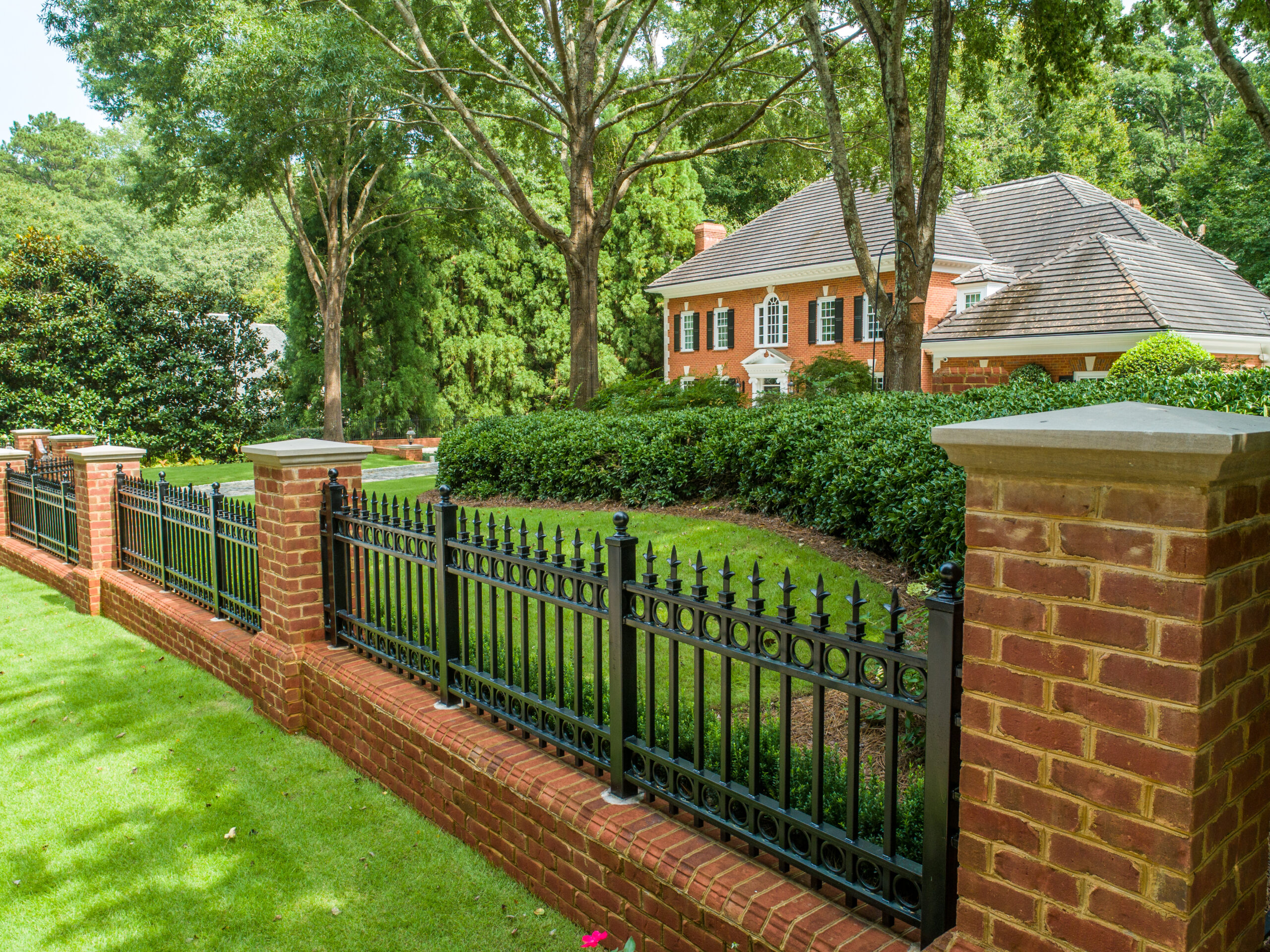 Wrought iron fence built into a brick wall in front of a brick house