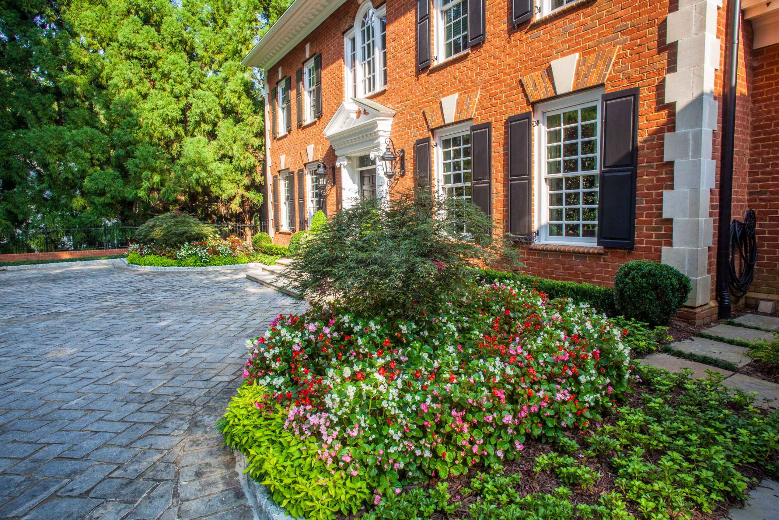 Brick home and landscaped front approach with ornamental fencing context
