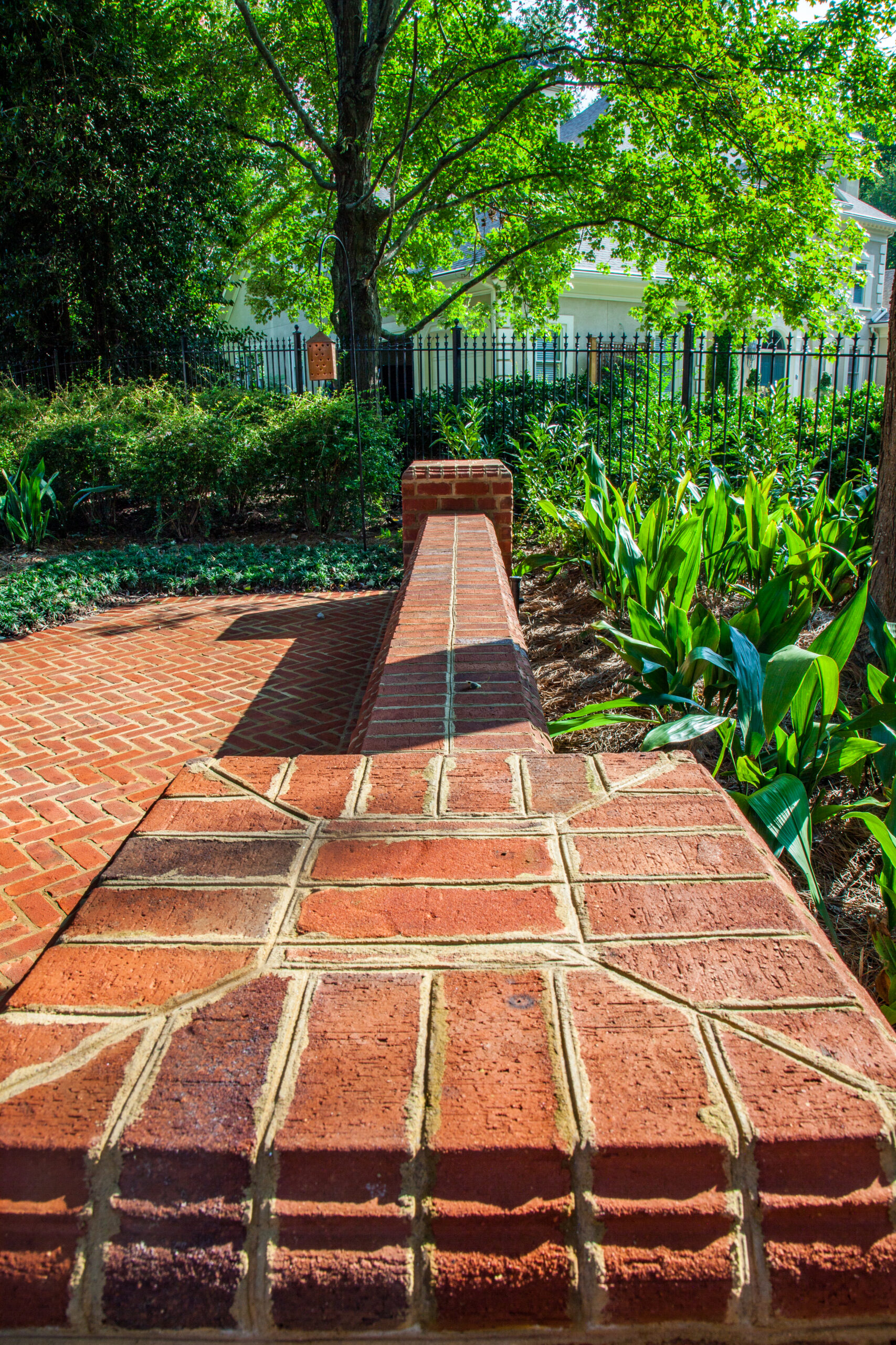Brick wall against a herringbone brick terrace surrounded by landscaping