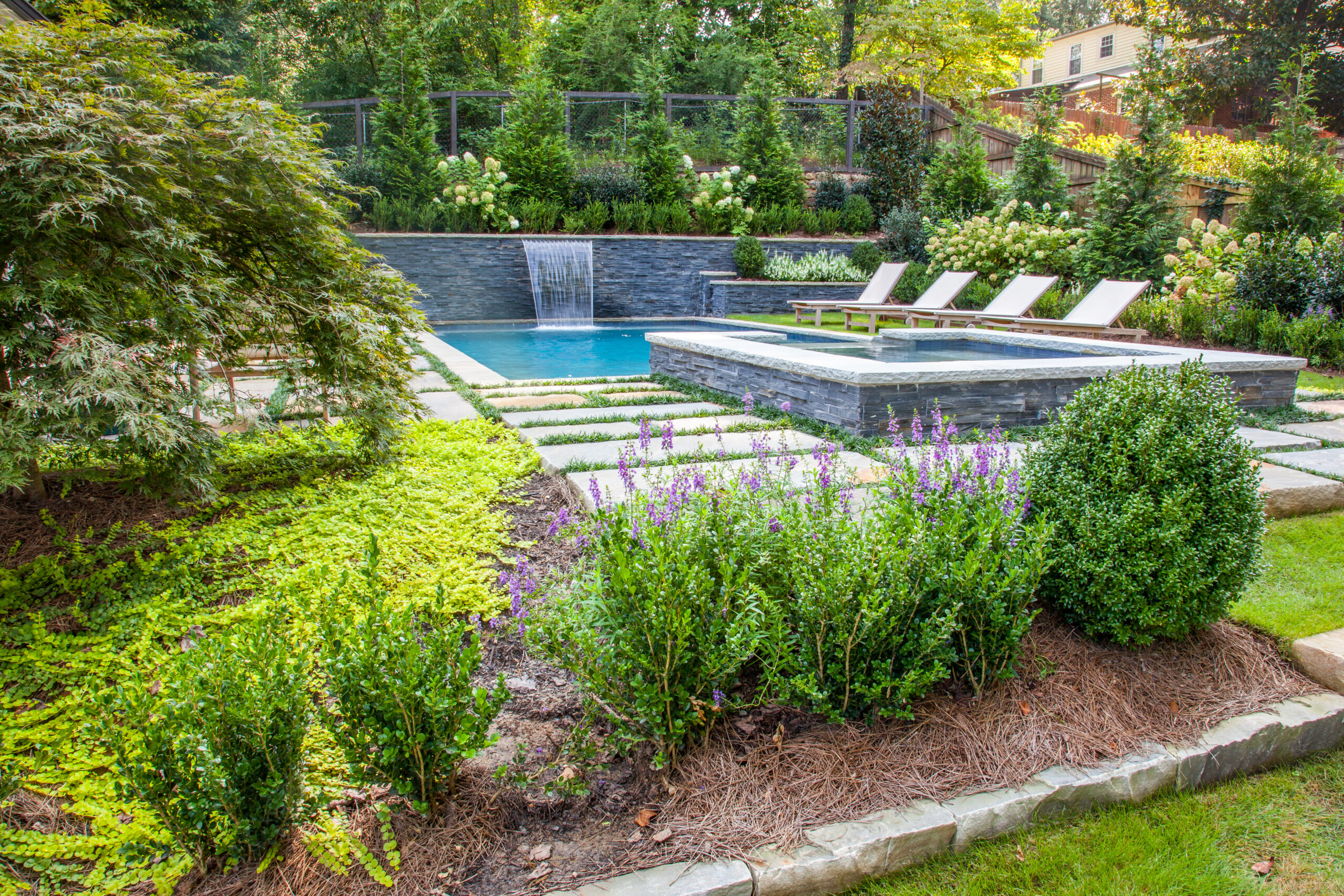 a lush backyard surrounded by greenery with a pool