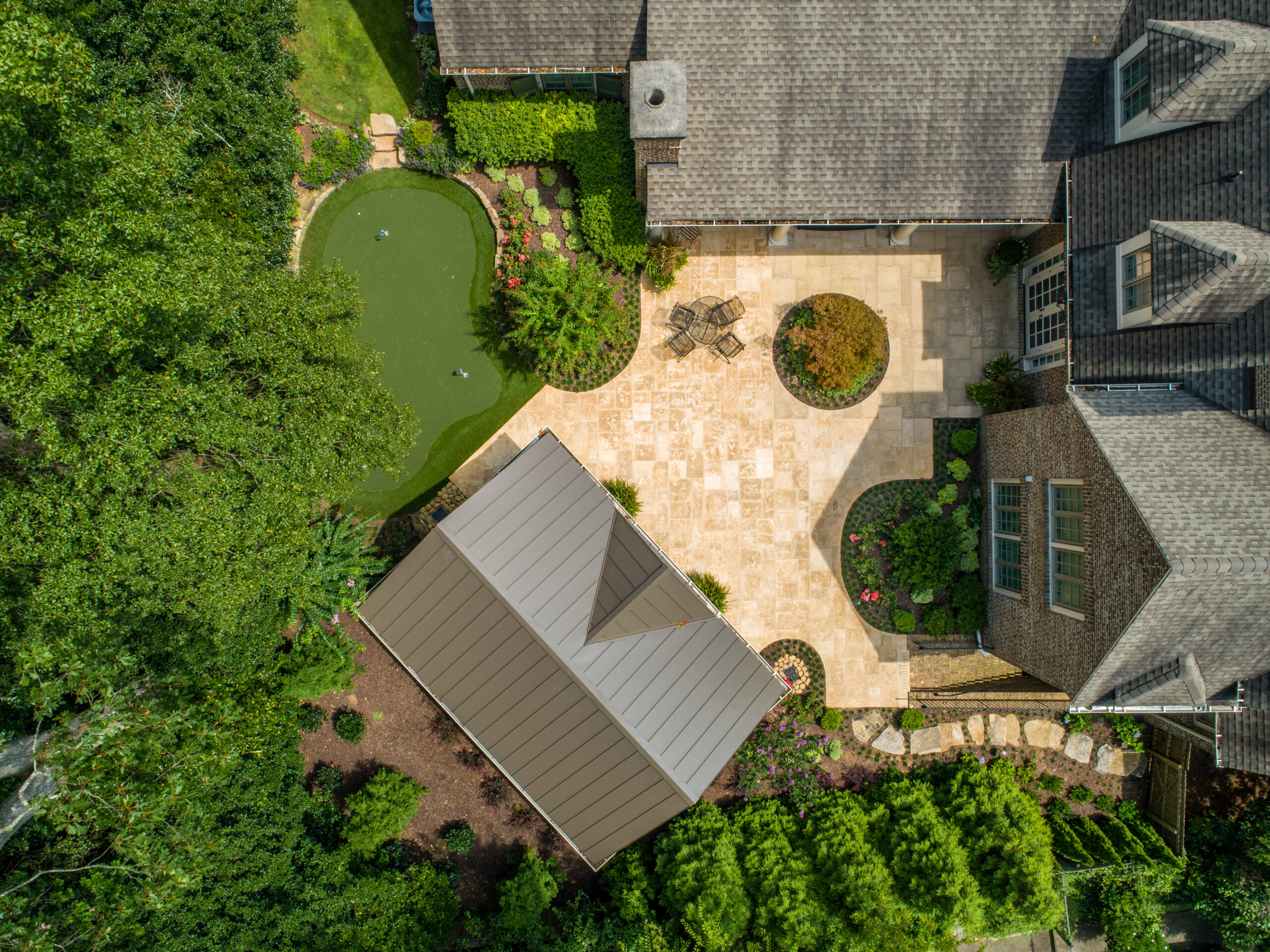 An overhead shot of a backyard and patio with gorgeous landscaping and a putting green