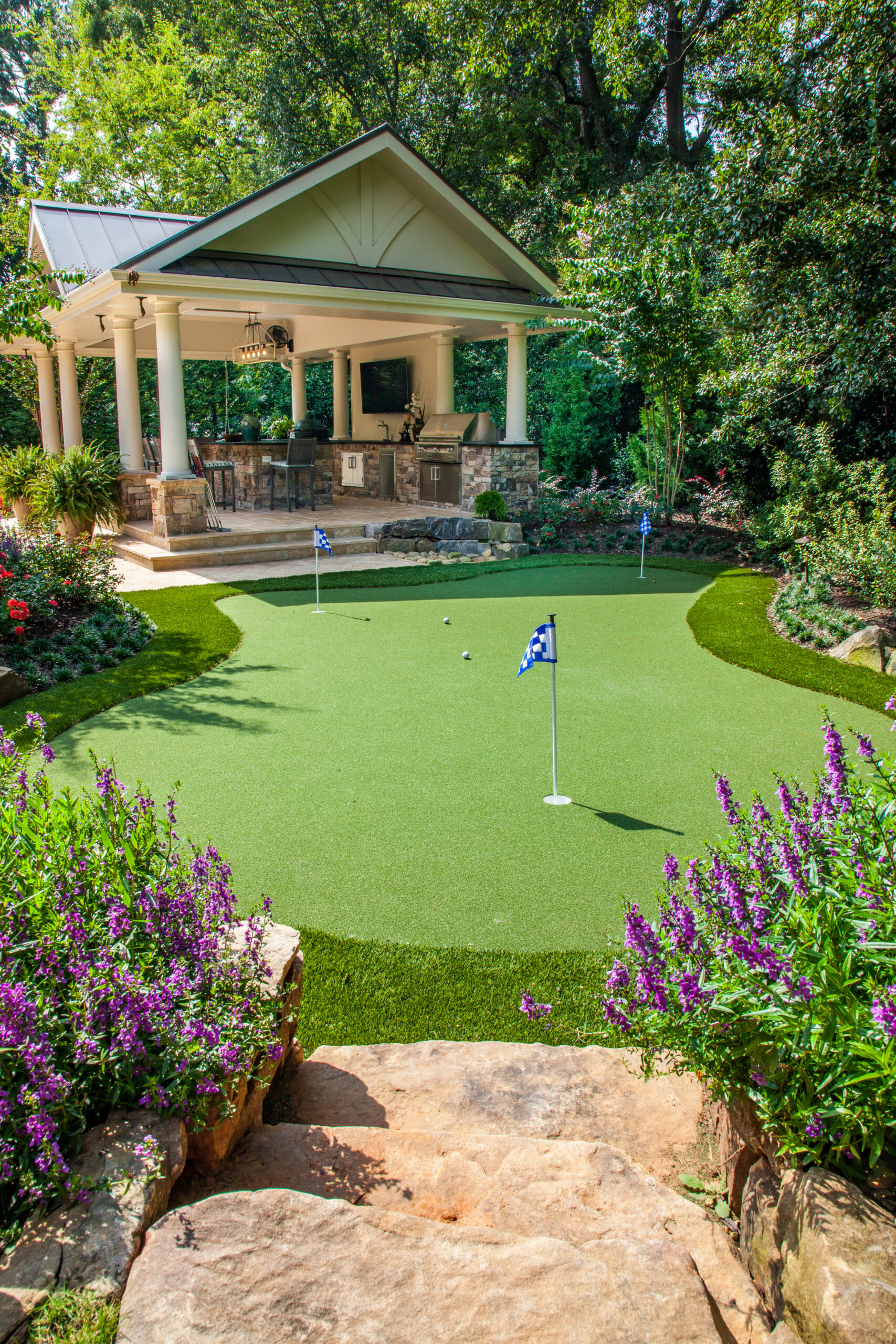 a gorgeous putting green in the backyard of a house and an outdoor kitchen