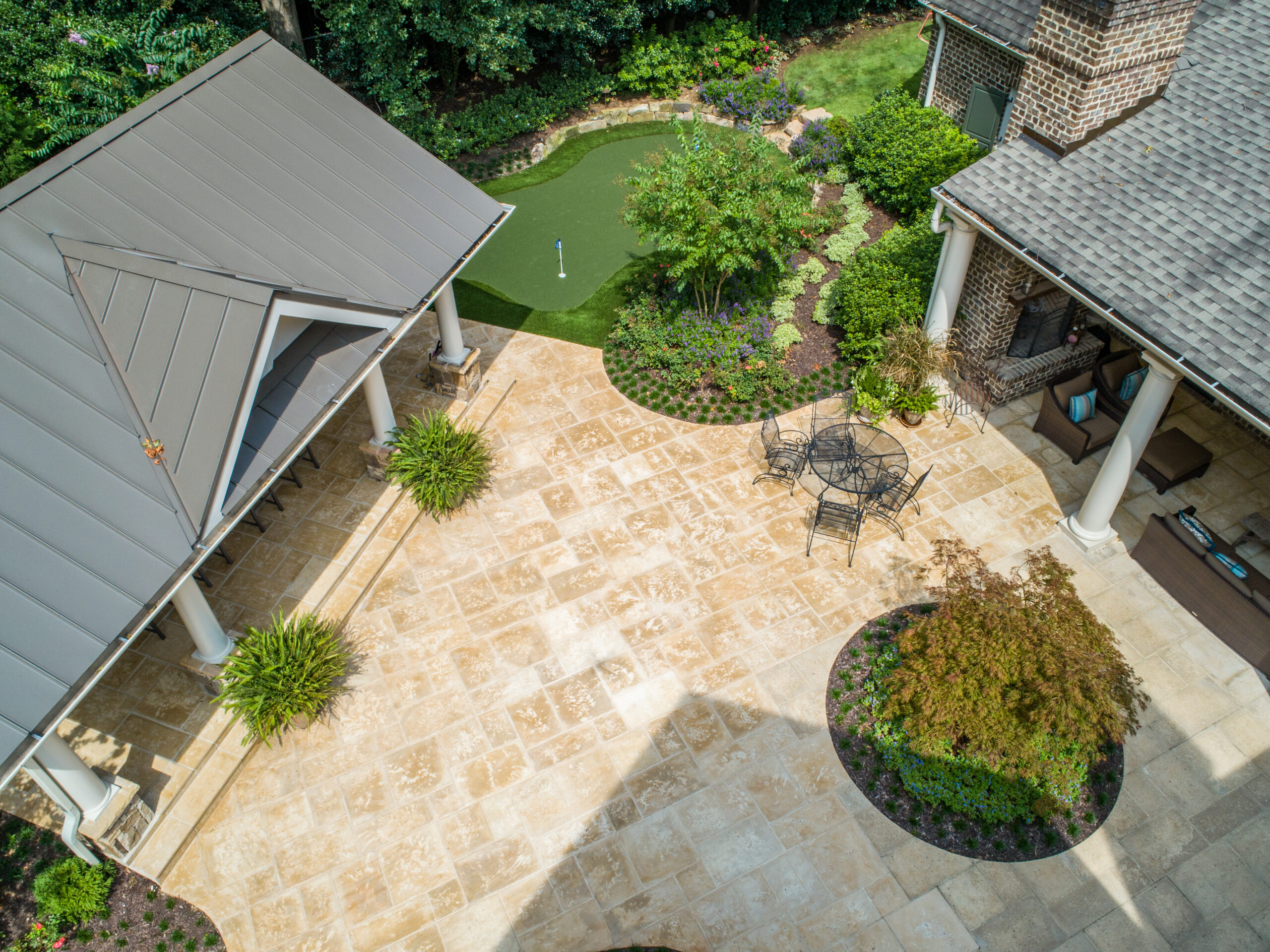 Aerial view of backyard with stone patio, putting green, and outdoor kitchen