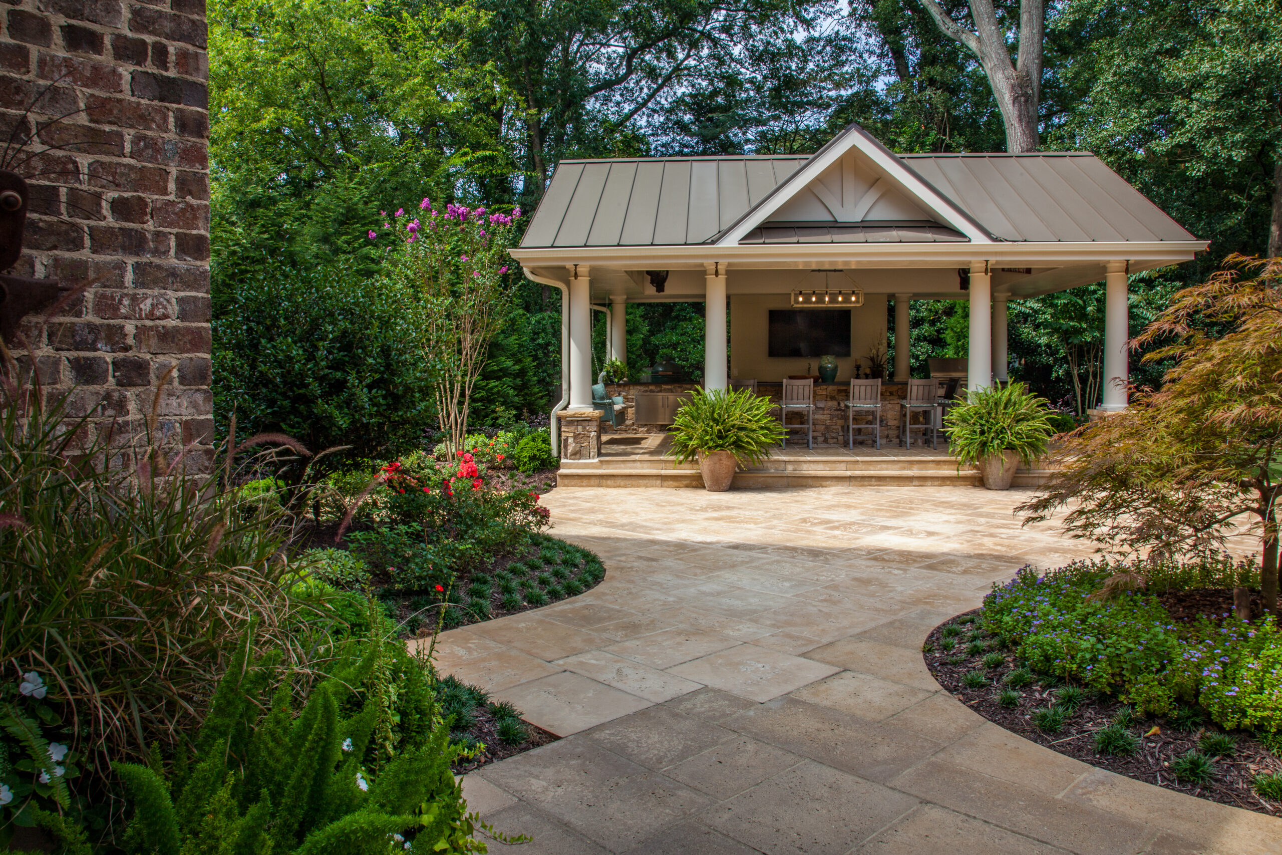 a covered outdoor kitchen with a hint of a modern farmhouse inspiration surrounded by greenery